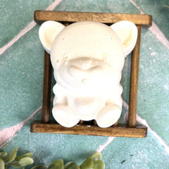 White ceramic pig on a wooden stand with a green tiled background. Baby soaps. Natural soaps. Tallow soap. Tallow product in DuBois Pa.