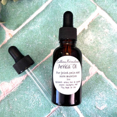 Bottle of Callhoun Farmstead Arnica Oil with dropper on a tiled surface