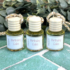 Three small bottles labeled 'Birthday Cake' on a green surface with leaves in the background. Birthday gift ideas. Gift shop near DuBois Pa.