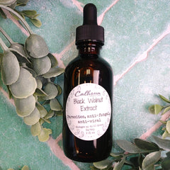 Bottle of Calhoun Black Walnut Extract with a dropper on a green leafy background
