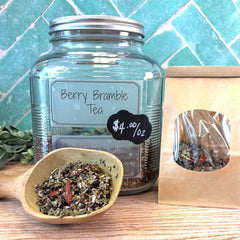 Glass jar of Berry Bramble Tea with a wooden scoop and packaging on a tiled background. Berry teas for iced tea. Herbal apothecary in DuBois Pa.