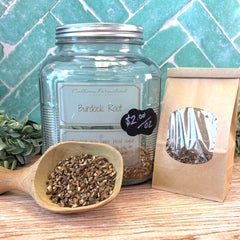 Jar of burdock root with a wooden scoop and packaging on a wooden surface. Herbal remedy store, DuBois Pa