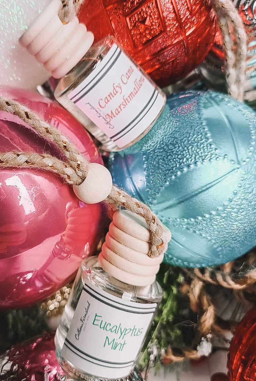 Two glass car air fresheners. Glass bottles with wooden lids. Hang in car and release essential oils. Scents in photo are Candy Cane Marshmallow and Eucalyptus Mint.