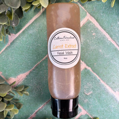 Facial wash bottle labeled 'Carrot Extract' on a green tiled background with green leaves. Carrot Face wash for sensitive skin