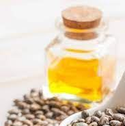 Castor oil in bottle with dish of castor beans in foreground.  