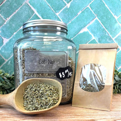 Glass jar labeled 'Catnip' with a wooden scoop and paper bag on a tiled background. Loose leaf tea blends sold in DuBois Pa