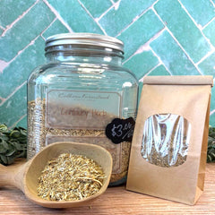Glass jar with 'Century Herb', wooden scoop, and paper bag on a wooden surface with a teal tiled wall background. Herbs that help Stimulate Appetite. Herbs for heartburn, bloating, and gas. Liver and gallbladder support.