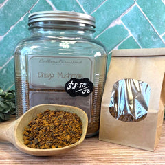 Glass jar with Chaga Mushroom and a wooden scoop on a wooden surface with a teal tiled wall background. Mushroom coffee for drinking hot or cold. Immunity boosting natural tea.