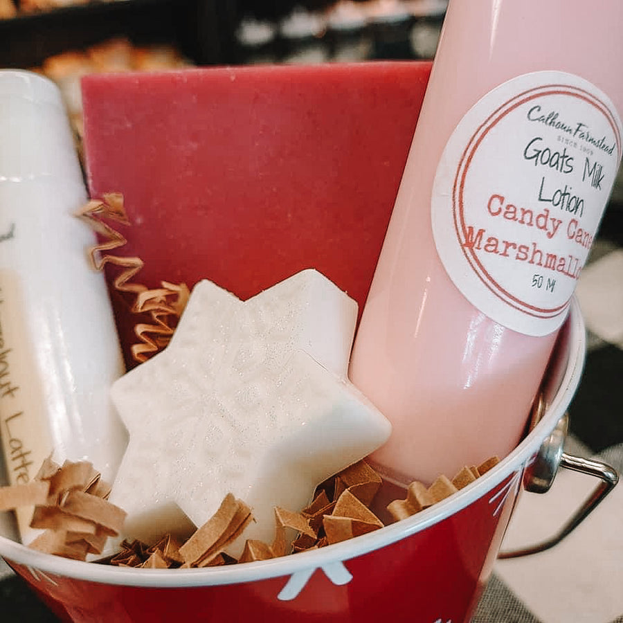 A close up shot of the goats milk gift set. Packed with goats milk lotion tubes, jumbo lip balm, square goats milk soap bar, and small guest soap in the shape of a snowflake.