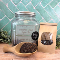 Cinnamon Orange Spice Tea jar with scoop and packaging on a wooden surface with green tiled background. Spice Tea. Cinnamon Orange tea.