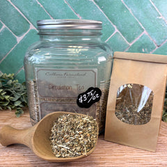 Glass jar of 'Circulation Tea' with a wooden scoop and packaging on a wooden surface. Herbs for heart health.