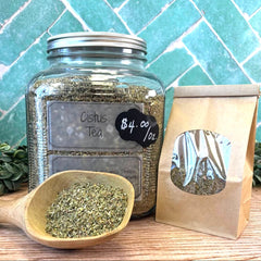Glass jar of Cistus Tea with a wooden spoon and paper bag on a tiled background. Lymes disease support and natural alternative remedies.