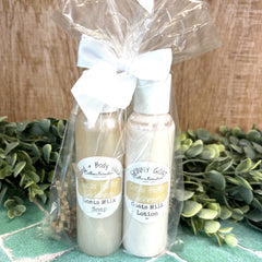 Two bottles of goat's milk soap and lotion with a white bow on a green tiled surface. Calhoun Farmstead. Herb store. DuBois Pa.