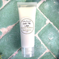 Tube of goats milk lotion with a label on a green tiled background