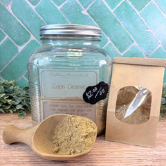 Glass jar labeled 'Colon Cleanse' with a wooden scoop and packaging on a wooden surface. Herbs for digestion. Natural ways to loosen stool.
