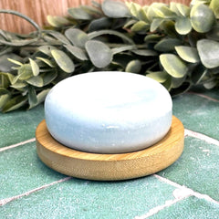 Light blue stone on a wooden stand with greenery in the background