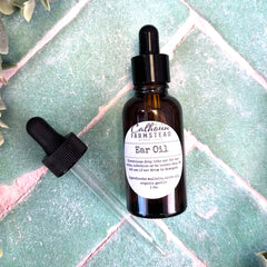Bottle of Ear Oil with dropper on a textured surface