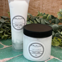 Two containers of Unscented Facial Lotion on a stone surface with greenery in the background. Face care with natural ingredients.