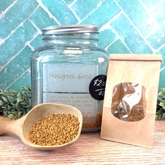Jar of fenugreek seeds with a scoop and packaging on a tiled background. Natural ways to increase breast milk production. Herbs to increase lactation.