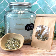 Glass jar of feverfew, small bowl, and paper bag on a wooden surface with a tiled background. Herbal remedy for headaches. 