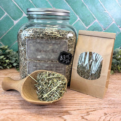 Herbal tea jar with a wooden scoop and packaging on a wooden surface with a green tiled background. Natural remedy for hot flashes. Menopause support.