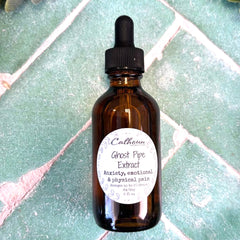 Brown glass bottle with dropper labeled 'Ghost Pipe Extract' on a green tiled surface.