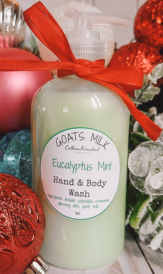 8oz pump bottle of Goats Milk Liquid soap. Hand  & Body Wash scented with Eucalyptus Mint. In front of a Christmas ornament backround.