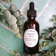 Bottle of Goldenrod Extract with a dropper on a green leafy background