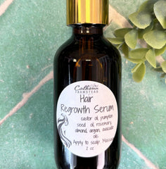 Hair regrowth serum bottle with dropper on a green leafy background. Castor oil, rosemary oil.