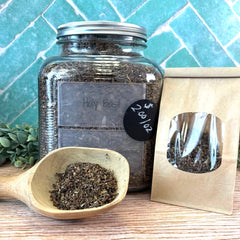 Jar of holy basil with a wooden scoop and packaging on a tiled surface. Benefits of Holy Basil. Old Fashioned remedies.