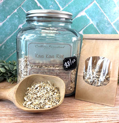 Glass jar of Kava Kava Root with a wooden scoop and packaging on a tiled background. Herb store offering teas, salves, balms, natural ingredients.