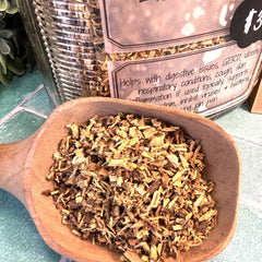 Wooden scoop filled with dried herbs on a green surface with a blurred background. Licorice Root Tea sold at Calhoun Farmstead in DuBois pa. Herb store.