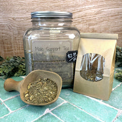 Clear jar labeled 'Male Support Tea' with a wooden scoop and packaging on a tiled surface. Tea for men. Herbs for men.