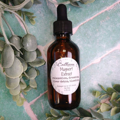 Bottle of Calhoun Mugwort Extract surrounded by mugwort leaves on a textured surface. Tinctures are taken orally.