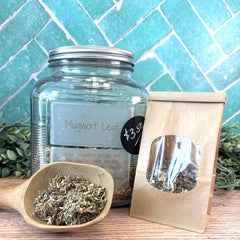 Jar of mugwort leaf with a wooden scoop and packaging on a tiled background. Herbs for sleep and dreaming. 