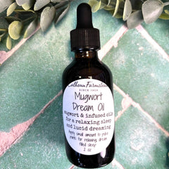 Bottle of Mugwort Dream Oil with dropper on a green tiled background