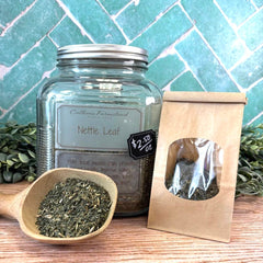 Jar of Calhoun Farmstead Nettle Leaf with a scoop and packaging on a wooden surface with a tiled background. Herbal apothecary DuBois Pa.