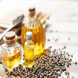 Castor oil in glass bottles surrounded by loose castor beans.