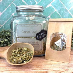 Jar of soursop leaf with a wooden scoop and paper bag on a tiled background. Herbs to kill cancer.