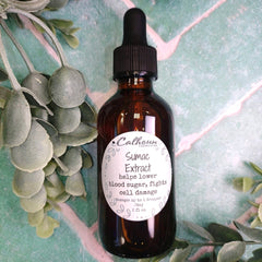 Brown glass bottle with dropper labeled 'Sumac Extract' on a green leafy background