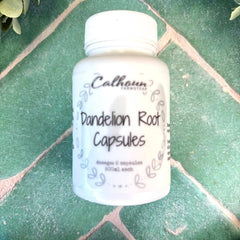 White bottle of Calhoun Naturals Dandelion Root Capsules on a green tiled surface with leaves around. Herb store