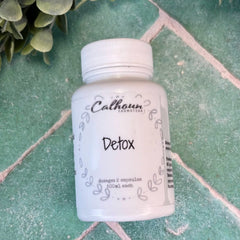 White bottle labeled 'Detox' by 'Calhoun Naturals' on a green tiled surface with green leaves.