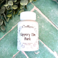 Bottle of Slippery Elm Bark on a green tiled surface with green leaves in the background