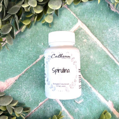 Bottle of Calhoun Spirulina on a green surface with leaves around