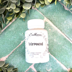 Calhoun Remedies Wormwood bottle on a green tiled surface with greenery around. Wormwood parasite cleanse.