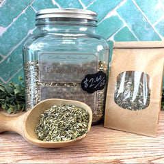 Clear glass jar with metal lid labeled 'Fennel Flower' on a wooden surface with a green tiled wall background. Natural ways to boost immunity. 