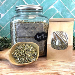 Glass jar of 'Moon Ease Tea' with a wooden scoop and packaging on a tiled background. Female tea. Feminine Tea. Period support. Menopause support.