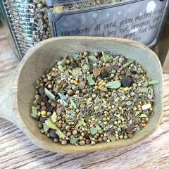 Herb mix in a wooden bowl with a label in the background. Spices for pickling - Pickles