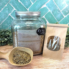 Glass jar labeled 'Sassafras Leaf' with a wooden scoop and packaging on a tiled background. Herbal teas. Herbal apothecary.