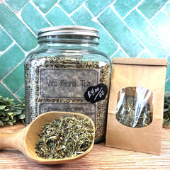Jar of Vita-Blend Tea with a wooden scoop and packaging on a tiled background. Clover, Nettle Alfalfa. Herbal blends